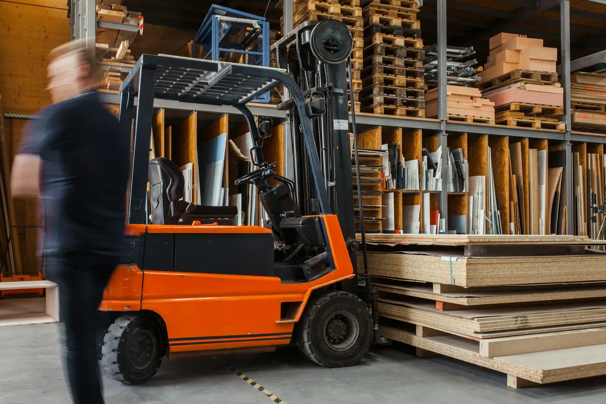 Byggmaterial på pallar i ett lager med truck